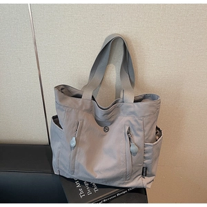 Detailed shot of dark grey nylon tote bag showing double front zipper pockets and side pouch