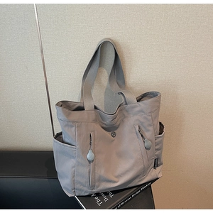 Detail of grey multi-pocket tote bag showing durable nylon material and zipper design