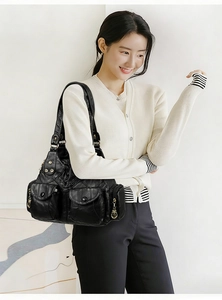 Detail of a soft black leather shoulder bag with multiple pockets and gold studs