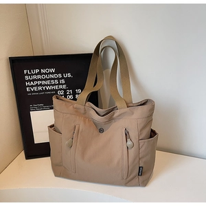 Macro shot of khaki nylon tote bag featuring vertical zipper pockets and sturdy carry handles