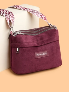Close-up of burgundy suede nylon bag with triple zipper pockets and jacquard strap