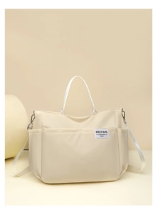 Close-up of beige multi-pocket nylon tote bag featuring durable straps and textile label