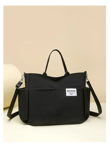Detail of durable black nylon crossbody bag featuring multi-pocket storage and brand label