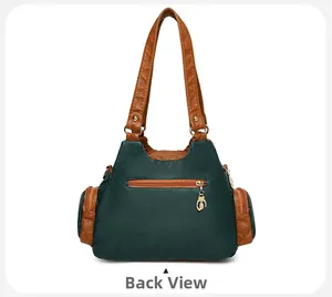 Back view of green and brown leather bag showing zipper pocket and cat charm
