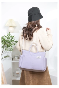 Detailed view of lavender nylon tote bag with multi-pocket design and brand label