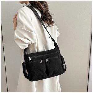 Détail du sac bandoulière en velours côtelé noir avec poches zippées et sangle large