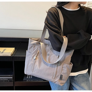 Detailed view of the multi-pocket nylon shoulder bag with Chuangmi woven label and zippers