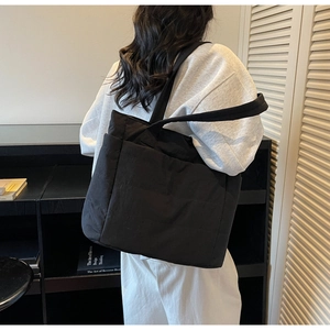 Rear view of a model wearing a large black quilted tote bag for daily commute fashion