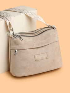 Detail of beige nylon crossbody bag featuring three zipper pockets and wave pattern strap