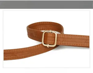 Close-up of adjustable brown pebbled leather bag strap with a gold square metal buckle