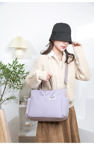 Detailed side view of a purple nylon tote bag on shoulder with adjustable strap and side pocket