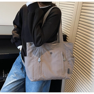 Detail of grey nylon tote bag showing vertical zipper pockets and CHUANGMI side label