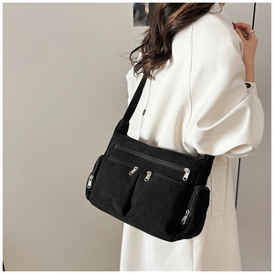Détail du sac bandoulière en velours côtelé noir avec poches zippées et bandoulière réglable