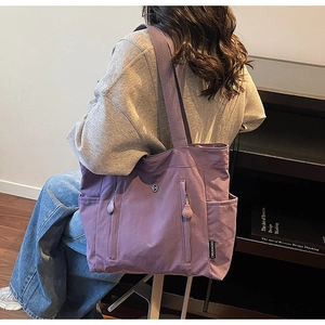 Detailed side view of purple nylon tote bag featuring side pockets and round logo