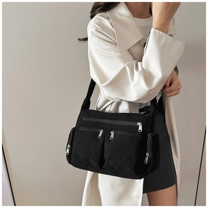 Détail du sac bandoulière en velours noir à fermetures éclair avec un trench-coat beige