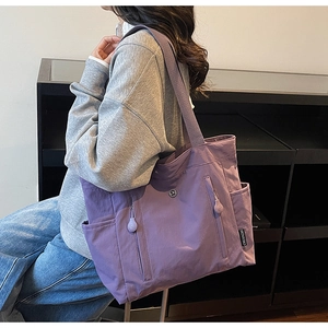 Detail of purple nylon tote bag showing side pockets and woven CHUANGMI brand tag