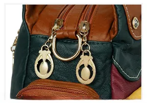 Detailed close-up of golden zipper pulls on a textured leather handbag with contrast stitching