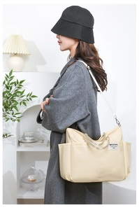 Close-up of beige nylon shoulder bag showing side pocket detail and woven brand label