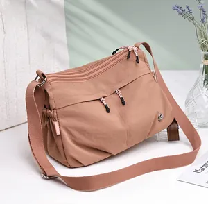 Detailed close-up of khaki waterproof nylon crossbody bag with multi-pocket zipper design