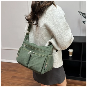 Détail du sac bandoulière en velours côtelé vert armée avec poches multiples sur mannequin