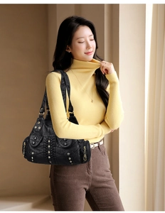 Close-up of black textured leather hobo bag with woven details and metal rivets