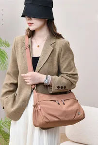 Detail of caramel nylon shoulder bag with wide strap and silver buckle on female model
