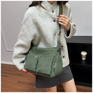 Détail du sac bandoulière en velours côtelé vert armée porté avec poches zippées