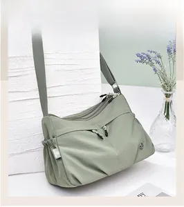 Close-up of green waterproof nylon crossbody bag with multi-zipper pockets and side strap