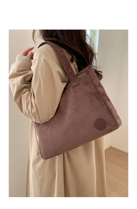 Detailed close-up of a large purple-brown suede tote bag with an embossed logo
