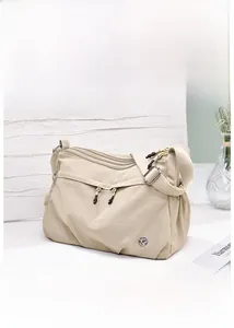 Detailed view of beige waterproof nylon crossbody bag with multi-zipper pockets