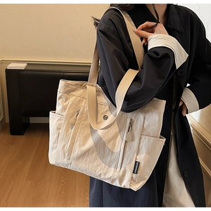 Detail of warm beige nylon tote bag with vertical zippers and woven shoulder strap