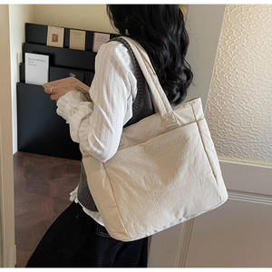 Detailed side view of a large cream tote bag showing soft nylon fabric and wide strap