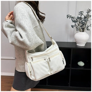 Détail d'un grand sac bandoulière en velours côtelé avec plusieurs poches zippées et sangle