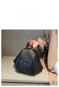 Detail of woven texture on black leather backpack with metal logo and front pocket