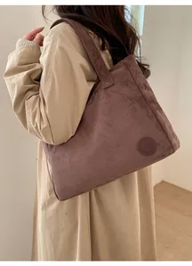Detail of suede tote bag showing its large capacity and embossed logo on the side
