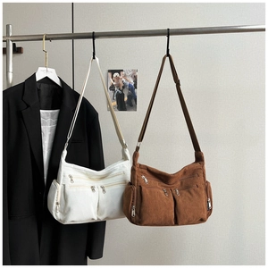 Détail de sacs bandoulière en velours côtelé avec plusieurs poches zippées en beige et marron