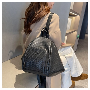 Detail of black woven leather backpack with metal logo and adjustable nylon straps