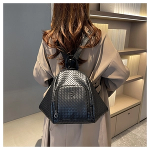Detail of black woven texture on women's backpack featuring metal kangaroo logo