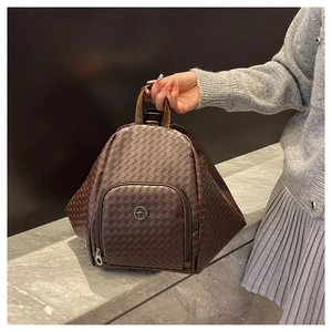Macro detail of dark brown woven texture and round metal logo on geometric backpack