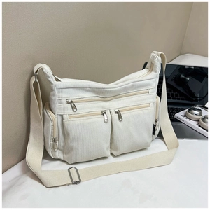 Gros plan du sac bandoulière en velours côtelé blanc avec poches multiples et zips en métal