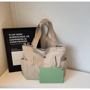 Detail view of large nylon tote bag with vertical zip pockets and wide shoulder straps