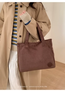 Detailed macro of dark coffee suede tote bag showing soft texture and embossed logo