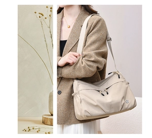 Detail of water-resistant beige nylon crossbody bag with multi-zipper pockets and wide strap