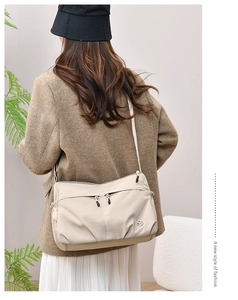 Beige nylon crossbody bag shown on a model in an urban leisure style setting