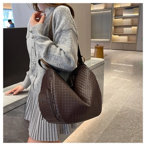 Detail of woven texture on dark brown tote bag featuring side zipper pocket and shoulder strap