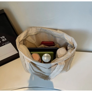 Detailed view of the spacious interior compartment with multiple pockets in the canvas tote bag