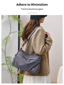 Waterproof nylon crossbody bag in dark grey worn by a model in a modern home setting