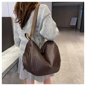 Detail of dark brown woven leather shoulder bag with wide strap and side zipper pocket