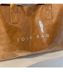 Close-up of brown Tyvek tote bag featuring bold white TOTE BAG text on glossy surface