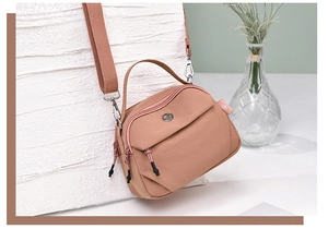 Détail du sac bandoulière en nylon rose avec zips et large bandoulière ajustable